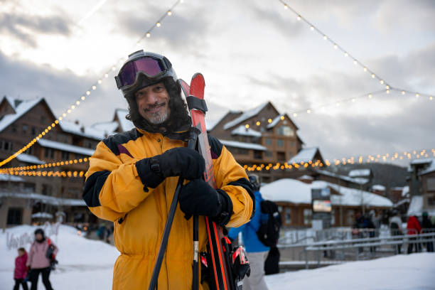 Portrait of a smiling man of Middle Eastern heritage posing with his skis beside the lodge at a resort in Winter Park, Colorado.