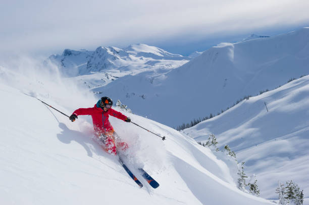 skier skis down slope through fresh powder snow - pista da sci immagine foto e immagini stock