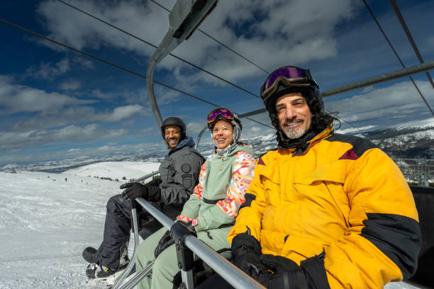 istock Three Friends Riding Ski Lift Smiling at Camera 2165025215
