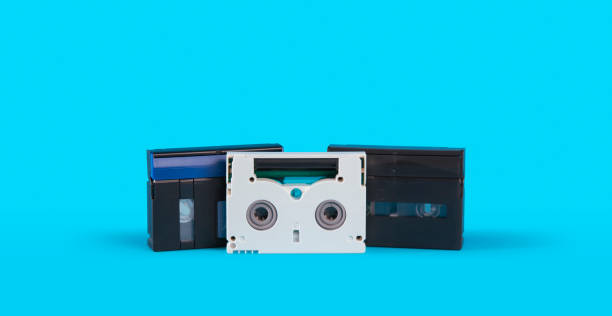 istock three old black and white colored mini DV cassette on a blue surface against blue background 2165025316