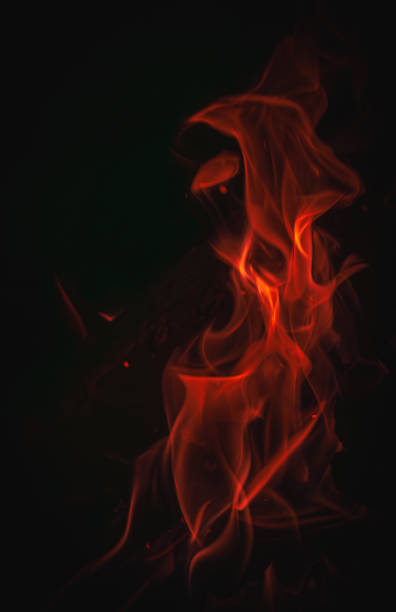 Red and orange flame isolated on a black background. Vertical photo of a wood burning at camp fire taken in June 2024 in Rigaud, Quebec, Canada.