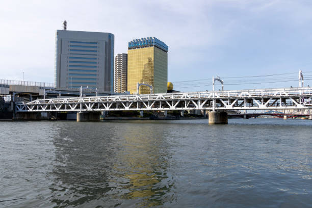 Tokyo, Japan- 11 May 2024: Railway bridge across Sumida river at Sumida River Walk park in Tokyo, Japan. Sumida River Walk is a structured way of seeing the attractions by the side of the river