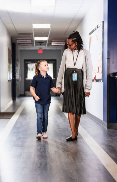 istock Elementary school teacher walking with girl in hallway 2165040701