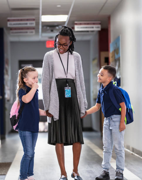 istock Elementary school teacher with two students in hallway 2165040705