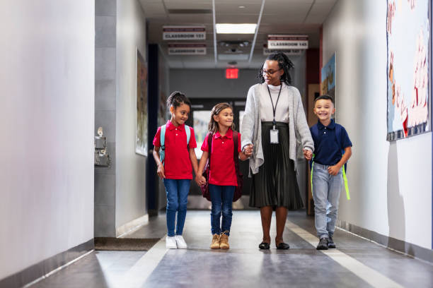 istock Elementary school teacher with three children in hallway 2165040725
