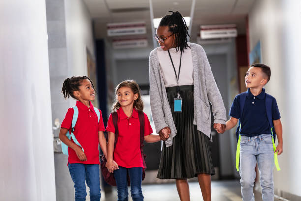 istock Elementary school teacher with three children in hallway 2165040728