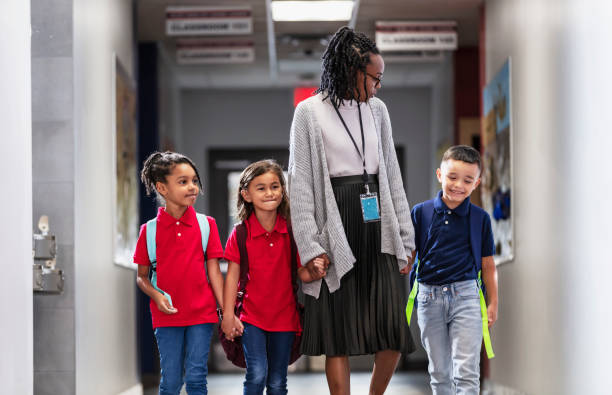 istock Elementary school teacher with three children in hallway 2165040732