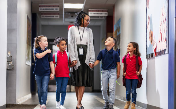 istock Elementary school teacher with four children in hallway 2165040734