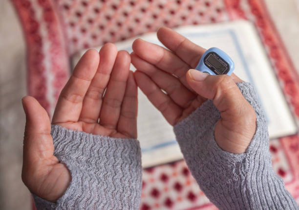 istock Close up of Asian Muslim woman's hand using modern digital prayer beads while praying after reading the Quran 2165042011
