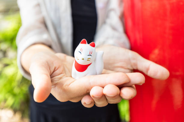 Inari Okami cute little fox god figure often seen at shrines in Japan held in woman's hands close up.