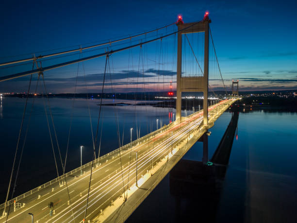 istock Suspension bridge at twilight with cars creating light trails 2165052756