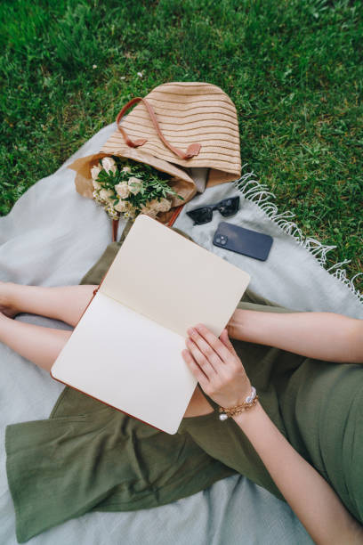 istock Woman relaxing on a picnic blanket with a journal 2165058503