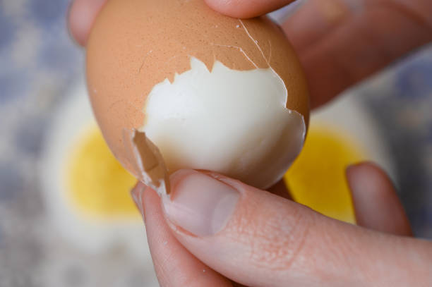 istock A woman peels the shell of a hard-boiled egg. 2165060088