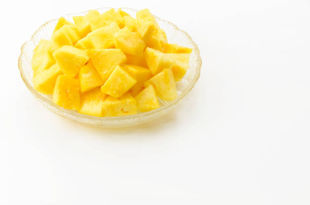 Pineapple chunks on a transparent glass dish on white background