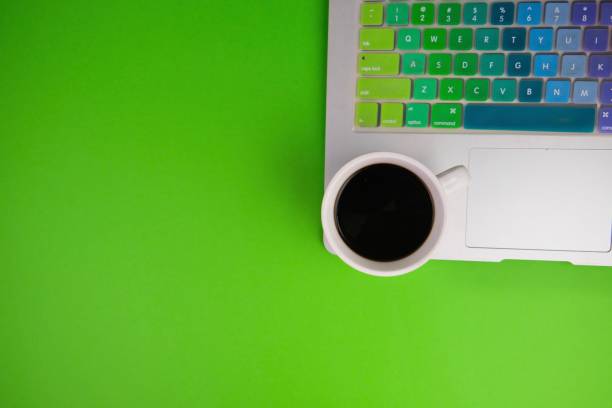 istock flatlay of a workplace with A cup of coffee, a laptop and a notebook, on a plain background. Education, business and office concept. 2165062374