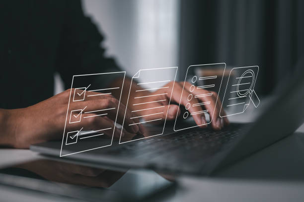 Hands on a laptop keyboard with checklists and files hovering above. It represents the integration of digital tools for streamlined task tracking, documentation, and effective project management. stock photo