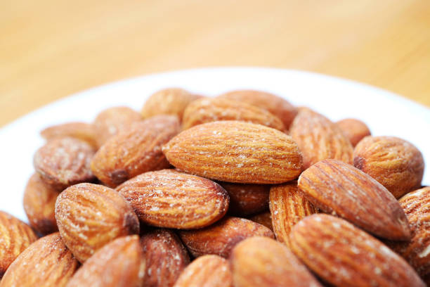 White Plate Full of Almonds Kernel Isolated on Wooden Table