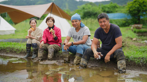 istock Portrait of Asian family taking break from working on rice field and resting together while eating food in rice field farm 2165073727