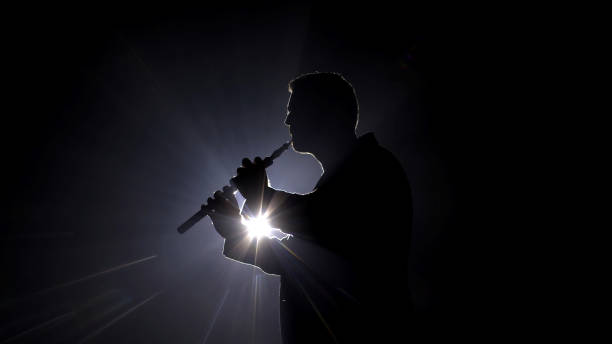 Silhouette of a man with a horn under stage lights. A striking image perfect for promoting live performances, musical events, and dramatic stage moments.