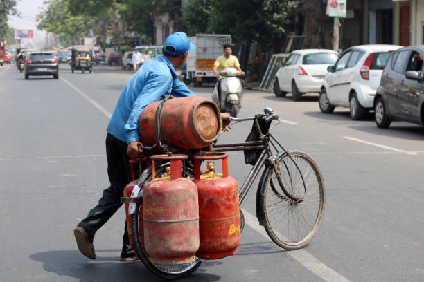 Rohtak, Haryana, India – June 02, 2018: Blue collar worker delivering LPG gas cylinder on cycle.