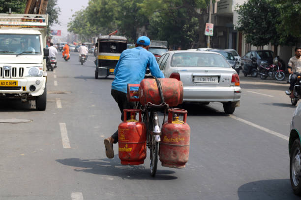 Rohtak, Haryana, India – June 02, 2018: Blue collar worker delivering LPG gas cylinder on cycle.
