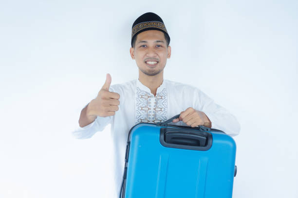 istock Moslem Asian man smiling and give thumb up while carrying suitcase 2165084107