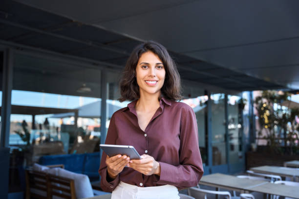 istock Portrait of middle eastern businesswoman using tablet pc app for work standing at office business building outdoors. Smiling indian or latin hispanic woman holding digital computer, looking at camera 2165098824