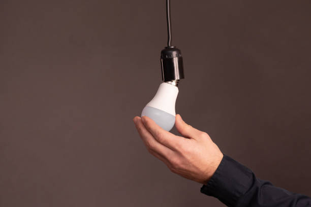 istock ale hands screw in an energy-saving LED light bulb. 2165099016