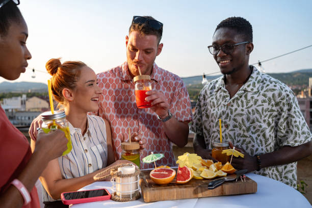 istock Friends having fun and drinking fresh fruit cocktails outdoors, rooftop gathering 2165111138
