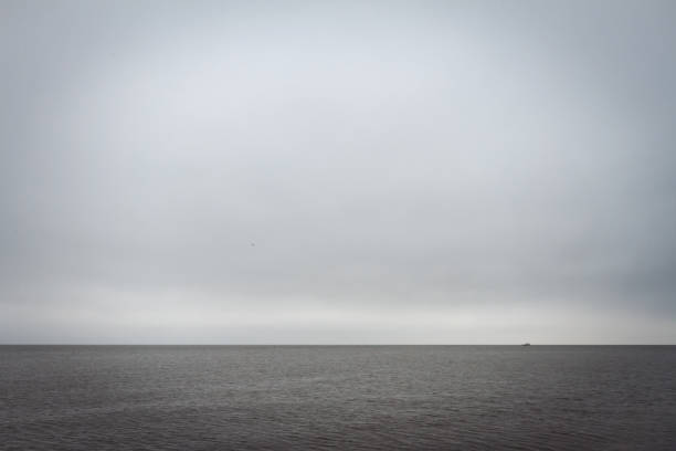 Sailing boats in calm bay coming through thick fog and morning mist. Moody atmosphere.