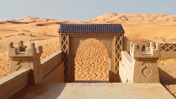 Jowzjan province, Afghanistan - August 30, 2024: A traditional adobe house in Sheberghan features striking blue doors, surrounded by arid land under a clear sky, reflecting local architecture.