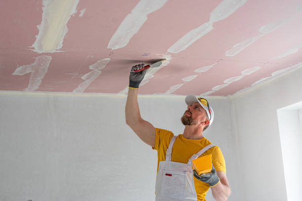 istock The worker make a plasterboard ceiling. He does taping plaster drywall ceiling joints. He is using special stainless steel taping knife. 2165130202
