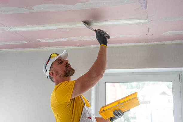 istock The worker make a plasterboard ceiling. He does taping plaster drywall ceiling joints. He is using special stainless steel taping knife. 2165130204
