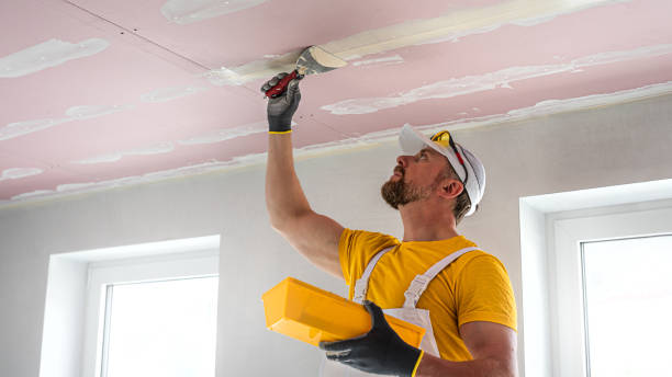 istock The worker make a plasterboard ceiling. He does taping plaster drywall ceiling joints. He is using special stainless steel taping knife. 2165130206