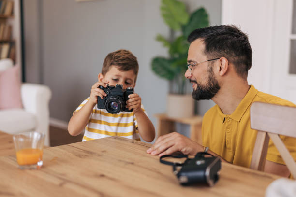 istock Boy focuses on camera while father guides beside him 2165132707