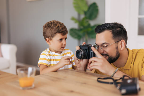 istock Young boy patiently observes as father operates camera 2165132752