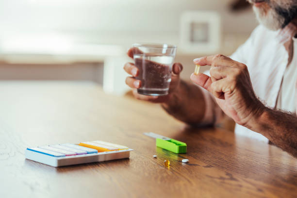 istock Senior Man Taking Medication With Pill Organizer And Water 2165132983