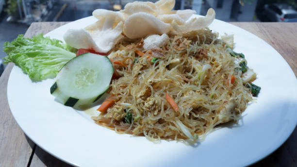 istock Freshly Prepared Stir-Fried Vermicelli with Vegetables and Crackers on a White Plate in a Well-Lit Restaurant Setting 2165139935