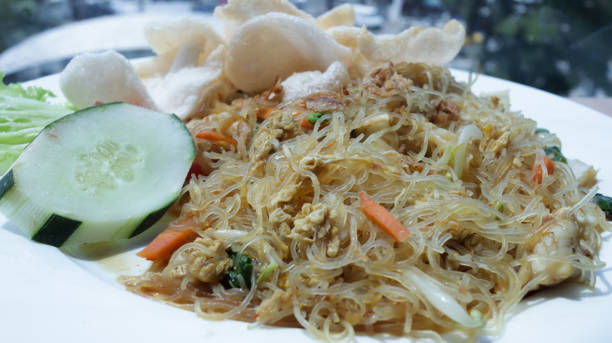 istock Freshly Prepared Stir-Fried Vermicelli with Vegetables and Crackers on a White Plate in a Well-Lit Restaurant Setting 2165139938