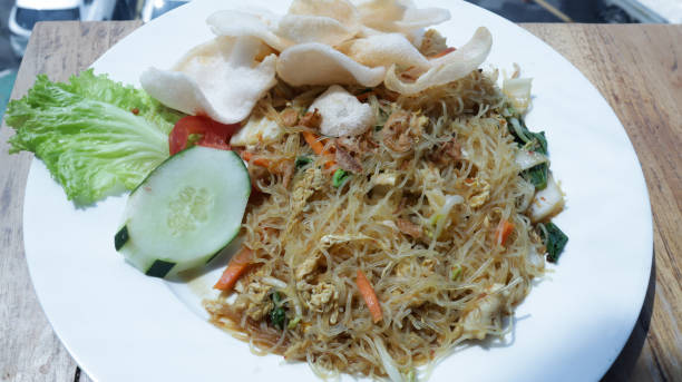 istock Freshly Prepared Stir-Fried Vermicelli with Vegetables and Crackers on a White Plate in a Well-Lit Restaurant Setting 2165139940