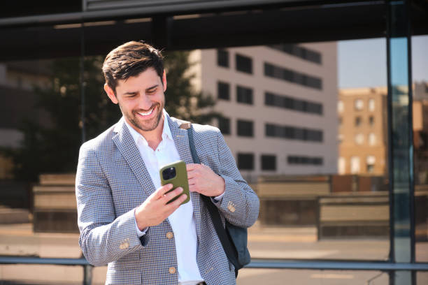 istock Young and handsome businessman smiling and reading a text message on smartphone 2165145415
