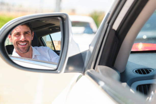 istock Businessman smiling and driving looking in rearview mirror 2165147712