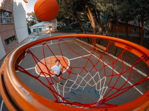 Young boy playing basketball in garden.
