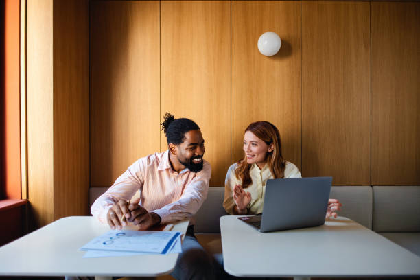 Business Meeting Between Colleagues Using Laptop In Office