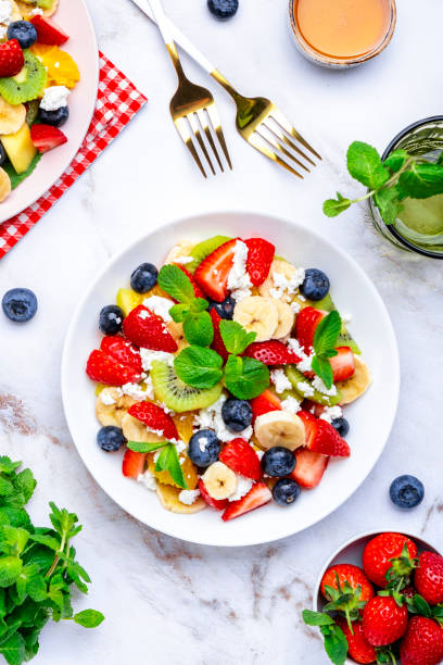 istock Fruit summer salad with berries, ricotta cheese, mint and honey, white marble background, top view 2165155487