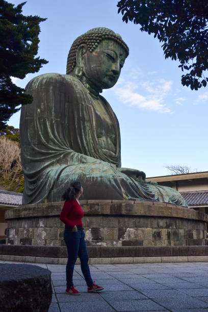 Woman looking back on a giant Buddha statue in Kotoku-in temple, Kamakura