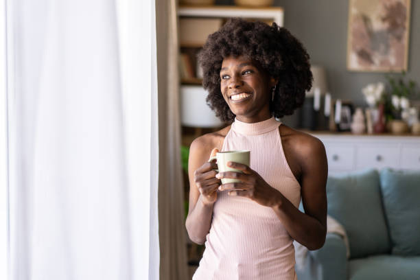 istock Smiling woman looking out of a window 2165160130