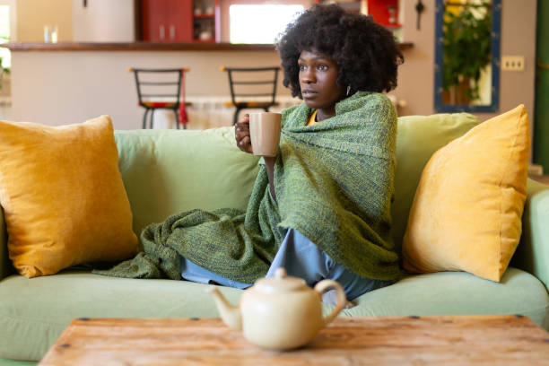 istock A woman suffering from a cold, wrapped in a blanket 2165160150