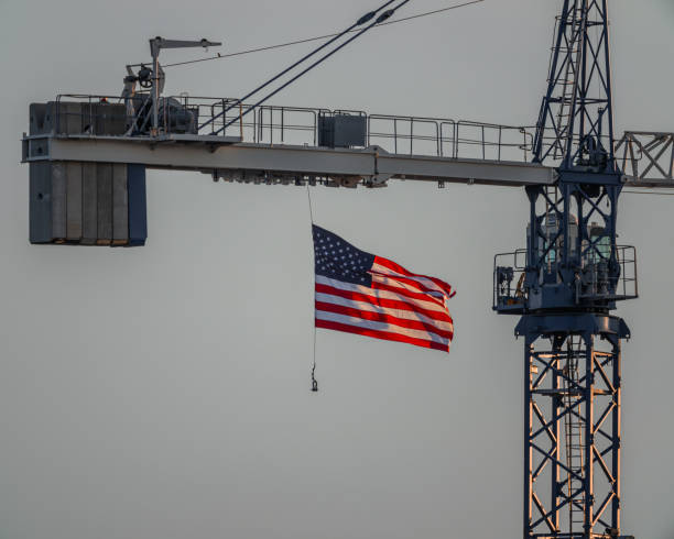 An American flag waves gently from a crane on a construction site, symbolizing pride amid an otherwise quiet and unassuming urban landscape.