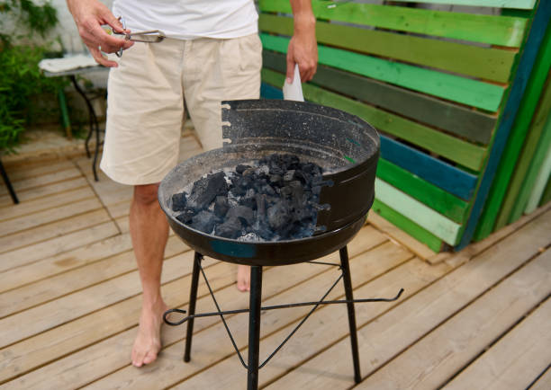 istock Man preparing charcoal grill on wooden deck for a backyard barbecue 2165165009